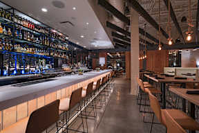 A bar with a long counter and chairs on either side.