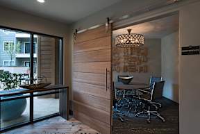 A conference room with a wooden door and a glass table with chairs.
