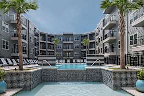 A pool surrounded by palm trees and apartment buildings.