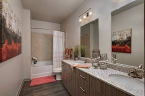 A bathroom with a large mirror, a bathtub, and a sink.