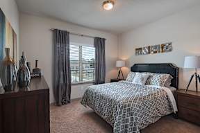 A bedroom with a large bed and a nightstand with a lamp.