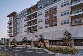 A modern apartment building with a parking lot in front.
