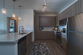 A modern kitchen with a granite countertop and stainless steel appliances.
