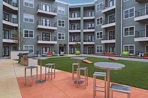 A patio with a table and chairs in front of apartment buildings.