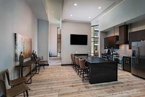 A modern kitchen with a bar area and a television mounted on the wall.