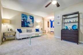 A living room with a white couch and a blue painting on the wall.