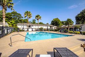A swimming pool surrounded by palm trees and a fence.