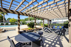 A patio with a table and chairs under a wooden pergola.