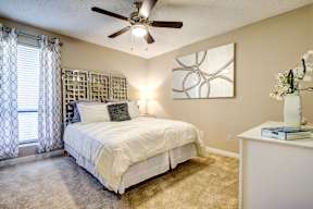 A bedroom with a large bed and a ceiling fan.