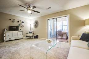 A living room with a white couch and a glass coffee table.