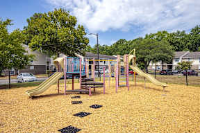 A playground with a yellow slide and a pink and blue play structure.
