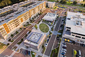 A parking lot with cars and a building with a glass facade.