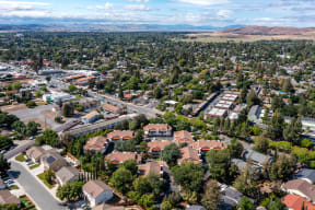 an aerial view of a neighborhood of houses with trees in the foreground and mountains in the background at Greentree Terrace Apartments, California, 94521
