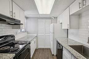 A kitchen with a black stove top oven and white cabinets.