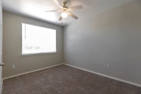 an empty bedroom with a ceiling fan and a window