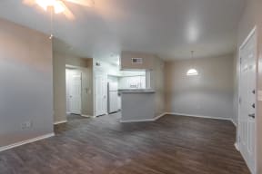 an empty living room and kitchen with wood flooring