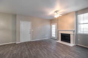 an empty living room with a fireplace and a ceiling fan