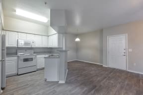 an empty kitchen and living room with white appliances and white cabinets