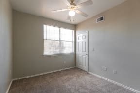 an empty bedroom with a ceiling fan and a window