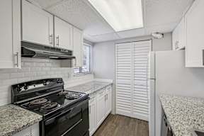 A kitchen with a black stove top oven and white cabinets.