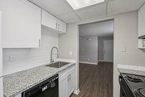 A kitchen with white cabinets and a granite countertop.