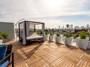 A wooden deck with a white planter and a chair.