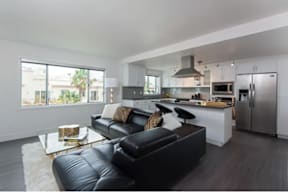 A black leather couch sits in a modern kitchen and living room.
