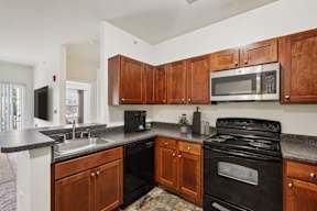 A kitchen with wooden cabinets and a black stove top oven.