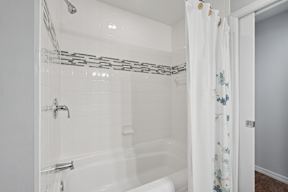 A white bathroom with a shower curtain and a white tub.