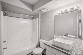 A white bathroom with a toilet, sink, and mirror.