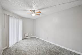 A room with a ceiling fan and carpeted floor.