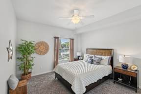 A bedroom with a large bed and a ceiling fan.