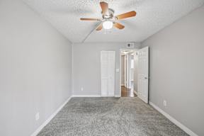 A room with a ceiling fan and carpeted floor.