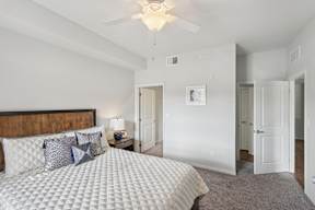 A bedroom with a large bed and a ceiling fan.