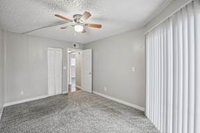 A room with a ceiling fan and carpeted floor.