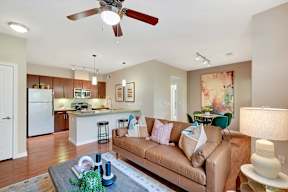a living room and kitchen with a couch and a ceiling fan