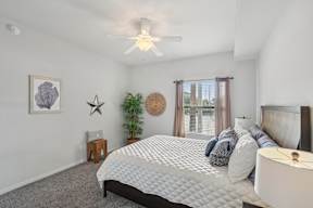 A bedroom with a large bed and a ceiling fan.