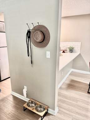 A hat and scarf hanging on a wall next to a bowl.