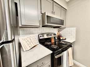 A kitchen with a black stove top and white cabinets.