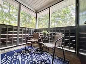 A patio with two chairs and a rug.
