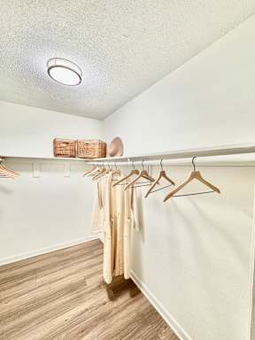 A row of clothes hanging on a rack in a room.