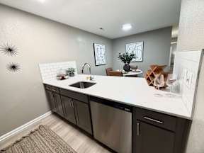 A modern kitchen with a white countertop and dark cabinets.