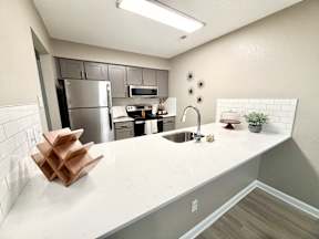 A kitchen with a white countertop and a stainless steel refrigerator.