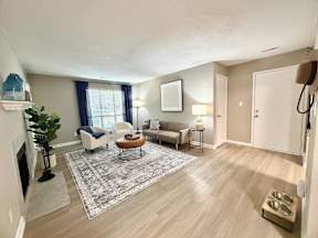 A living room with a fireplace, two chairs, a couch, and a rug.