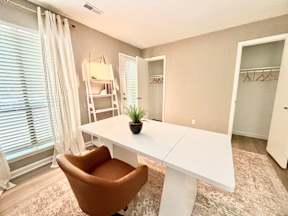 A white desk with a brown chair in a room with a window.