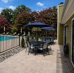 A patio with a table and chairs and a pool in the background.