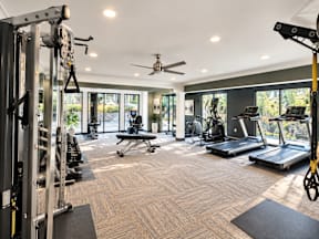 A spacious gym with a variety of equipment and a ceiling fan.