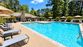 A large swimming pool surrounded by lounge chairs and umbrellas.