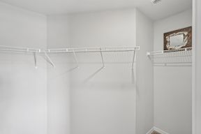 Empty white closet with a mirror on the wall.