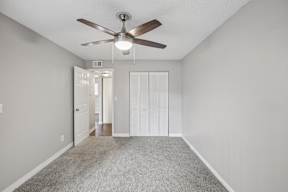 A room with a ceiling fan and carpeted floor.